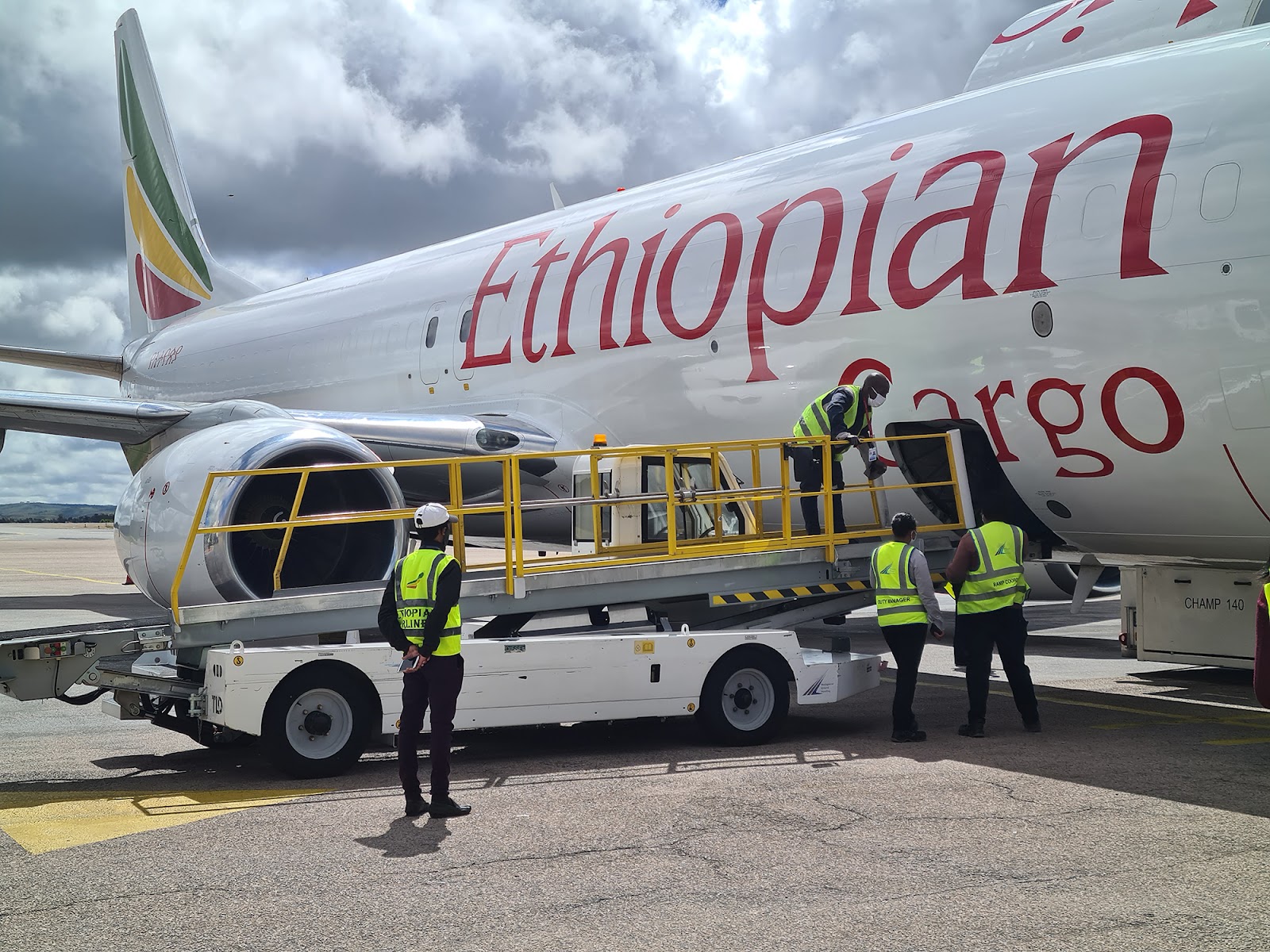 Four baggage handlers finish loading cargo onto an Ethiopian Airlines plane.
